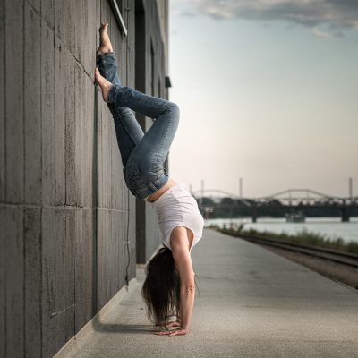 Frau lehnt sich im Handstand an eine Wand - Yoga